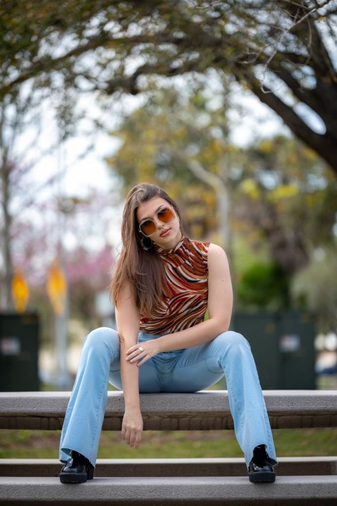 woman in blouse and jeans sitting on bench